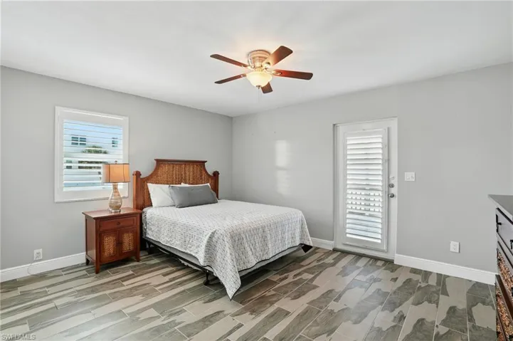 Bedroom with wood finish floors, ceiling fan, and access to exterior- Virtually Enhanced