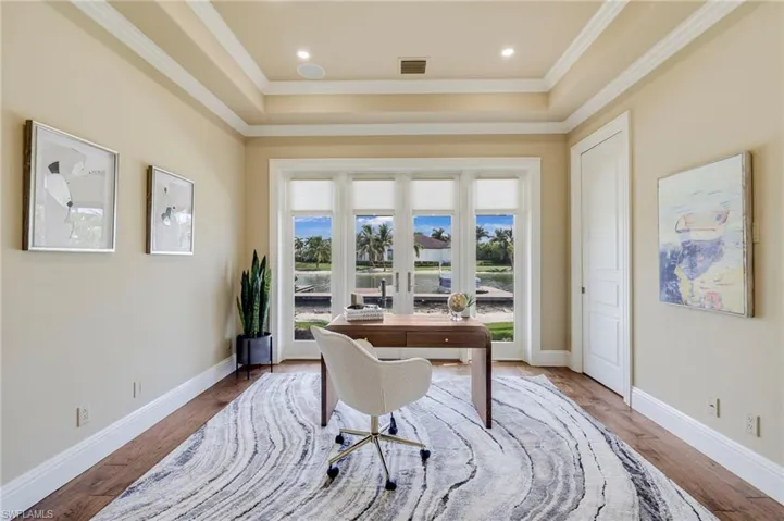 Office area featuring hardwood / wood-style floors, a tray ceiling, ornamental molding, and french doors
