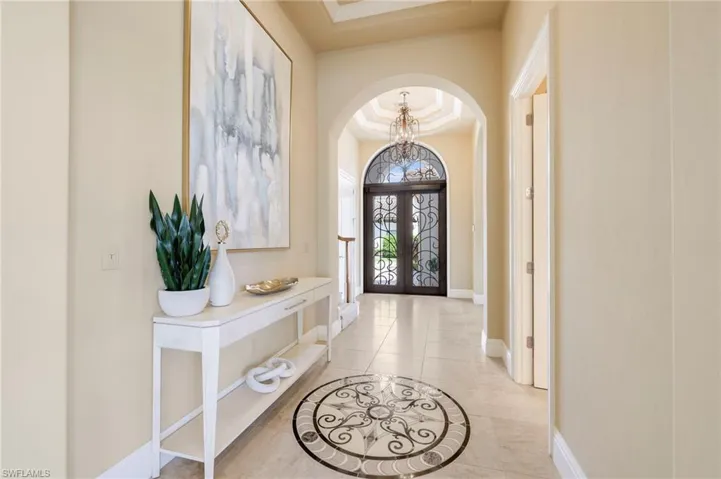 Tiled foyer featuring a tray ceiling and a chandelier