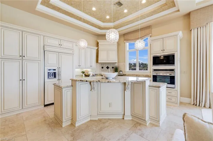 Kitchen with built in appliances, pendant lighting, a raised ceiling, and a center island