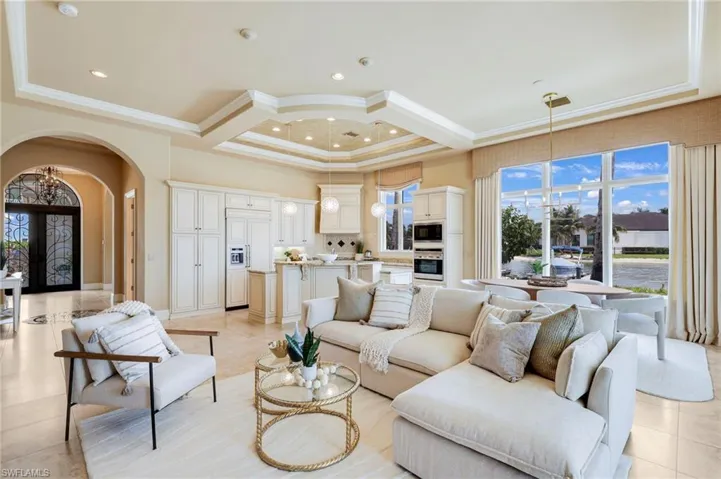 Tiled living room featuring coffered ceiling, a chandelier, and ornamental molding
