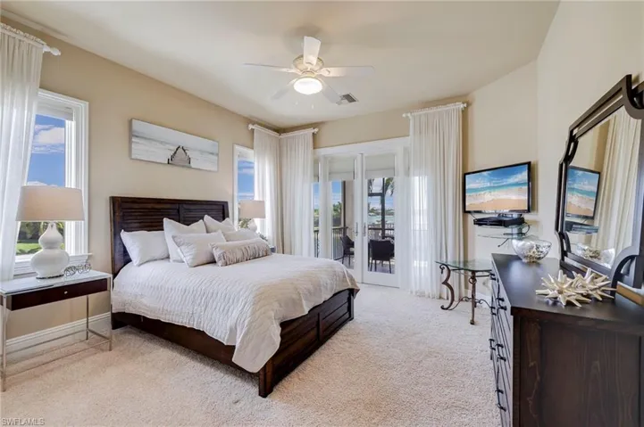 Carpeted bedroom with french doors, ceiling fan, multiple windows, and access to outside