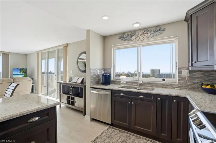 Kitchen with light stone countertops, dark wood finish cabinets, and stainless steel appliances - Virtually Edited Image