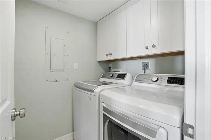 Laundry room featuring electric panel, washer and dryer, and cabinet space - Virtually Edited Image