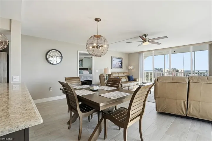 Dining room featuring hanging lights, ceiling fan, and expansive windows - Virtually Edited Image