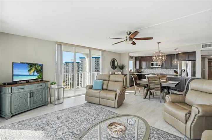 Living room featuring a ceiling fan, a chandelier, light wood-style flooring, and floor to ceiling windows - Virtually Edited Image