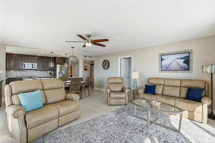 Living room featuring a ceiling fan, light wood finished floors, and hanging lights - Virtually Edited Image