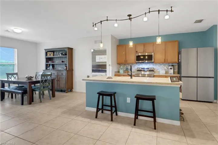 Kitchen featuring tasteful backsplash, a kitchen breakfast bar, stainless steel appliances, and a center island with sink