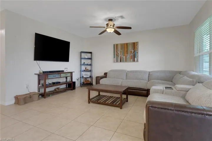 Living room with ceiling fan and light tile patterned flooring