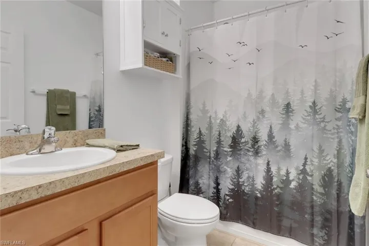 Bathroom featuring toilet, vanity, walk in shower, and tile patterned flooring