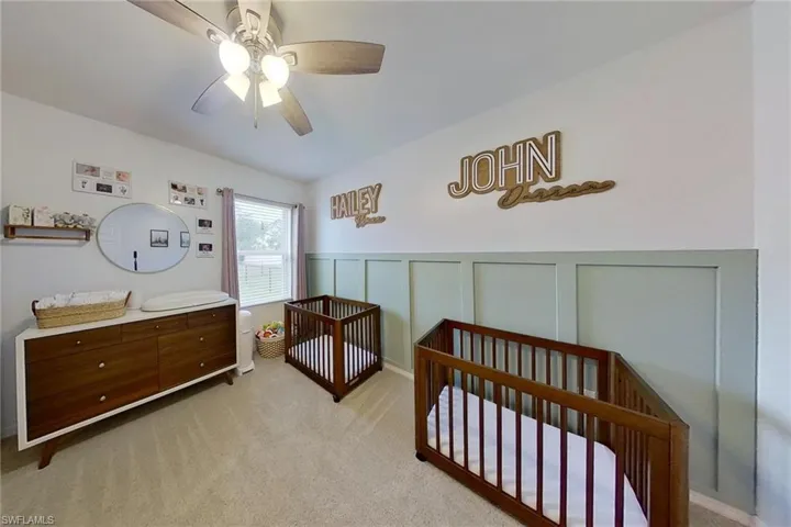 Carpeted bedroom with ceiling fan and a crib