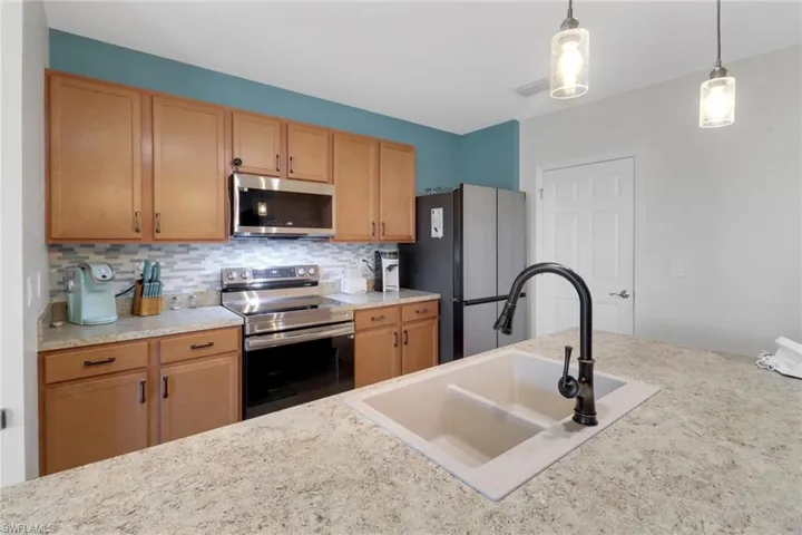 Kitchen with decorative light fixtures, decorative backsplash, sink, and stainless steel appliances