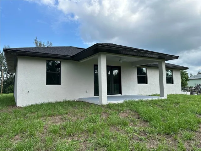 Back of house featuring ceiling fan, a yard, and a patio area