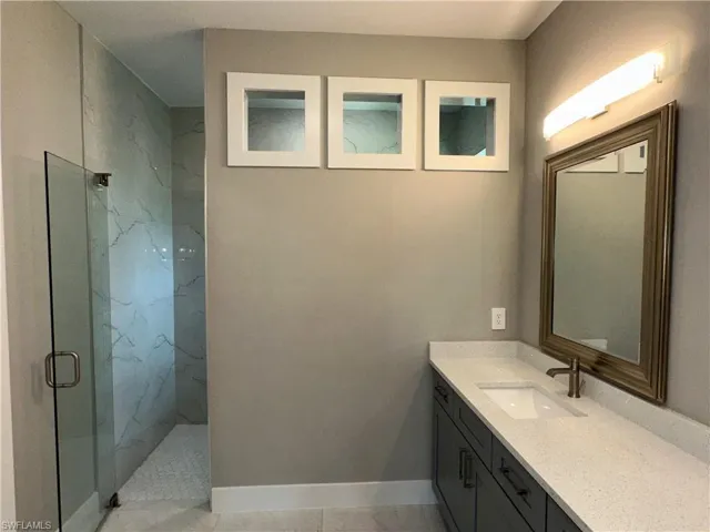 Bathroom featuring tile patterned flooring, an enclosed shower, and vanity