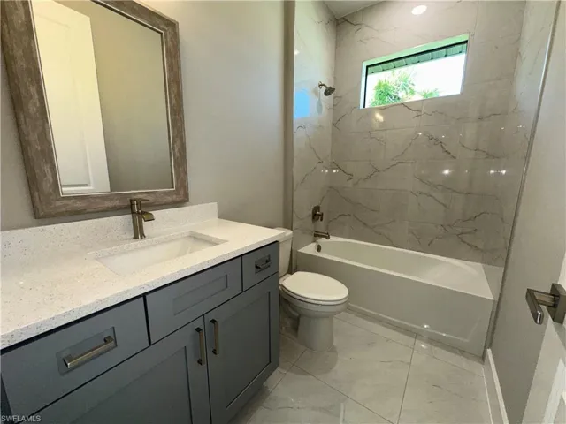 Full bathroom featuring tiled shower / bath combo, tile patterned floors, toilet, and vanity