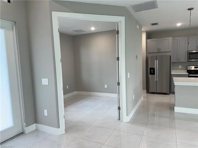 Kitchen with light tile patterned floors, appliances with stainless steel finishes, pendant lighting, and gray cabinets