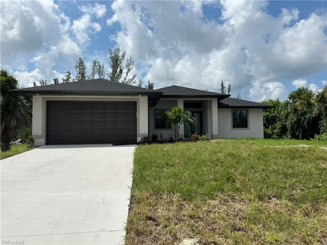 View of front of property with a garage and a front lawn
