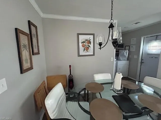 Dining room with crown molding and an inviting chandelier