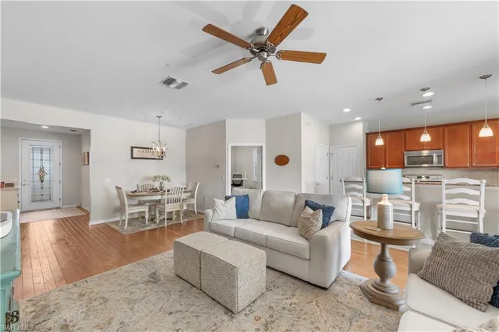 Living room with light wood-style floors, a ceiling fan, recessed lighting, and a chandelier