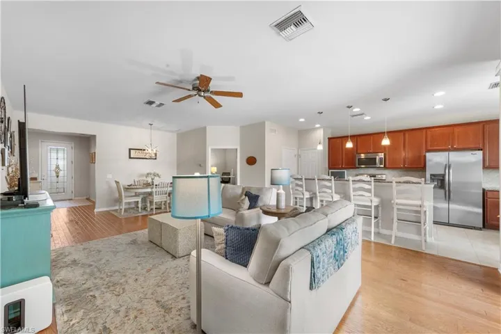 Living room featuring light wood finished floors, a ceiling fan, recessed lighting, and a chandelier