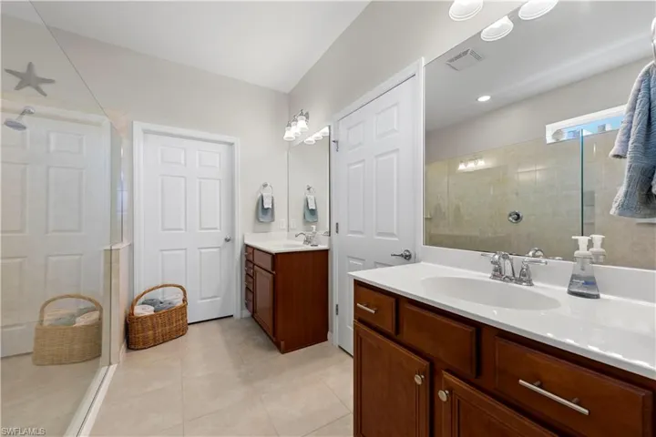 Bathroom featuring tiled shower, two vanities, and tile patterned flooring