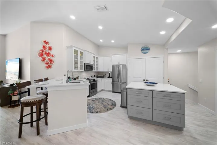 Kitchen with glass insert cabinets, a breakfast bar, stainless steel appliances, vaulted ceiling, and decorative backsplash