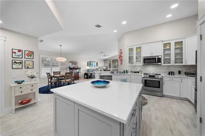 Kitchen featuring stainless steel appliances, a peninsula, white cabinetry, decorative backsplash, and glass insert cabinets