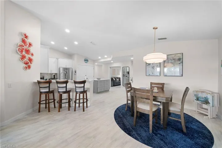 Dining space with light wood-style floors, lofted ceiling, and recessed lighting