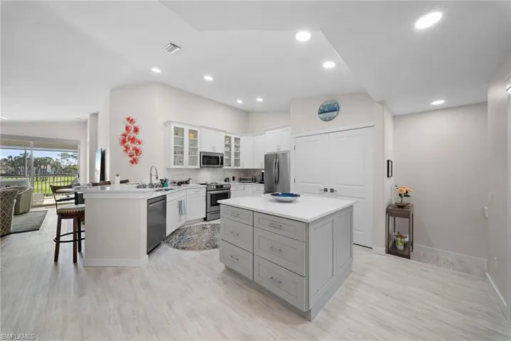 Kitchen featuring a peninsula, glass insert cabinets, a kitchen breakfast bar, stainless steel appliances, and decorative backsplash