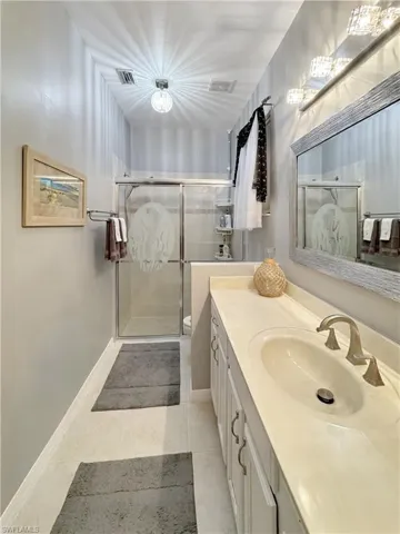 Bathroom featuring tile patterned flooring, vanity, and tiled walk in shower