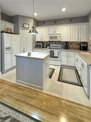 Kitchen featuring decorative backsplash, pendant lighting, light tile patterned floors, Corian counter top and sink, pantry