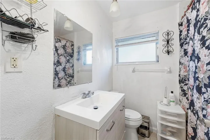 Bathroom featuring a shower with shower curtain, vanity, and a textured wall