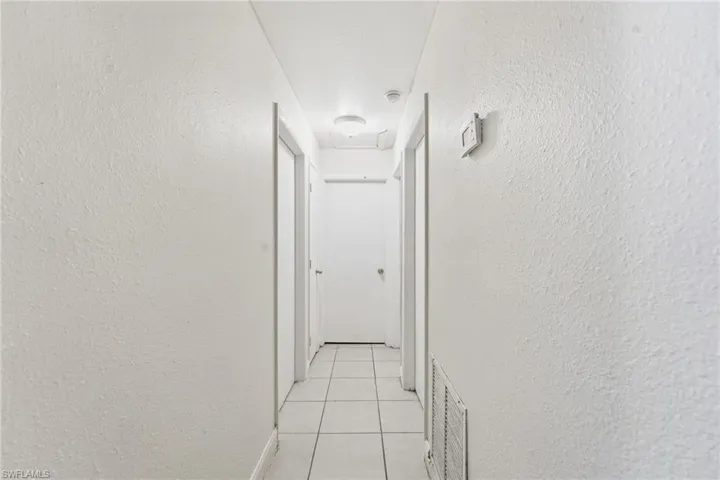 Corridor featuring a textured wall and light tile patterned floors