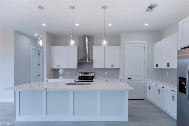 Kitchen with light stone countertops, stainless steel appliances, and white cabinets