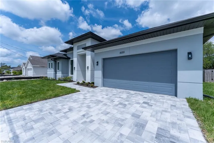 View of front of house with a front yard, stucco siding, and driveway