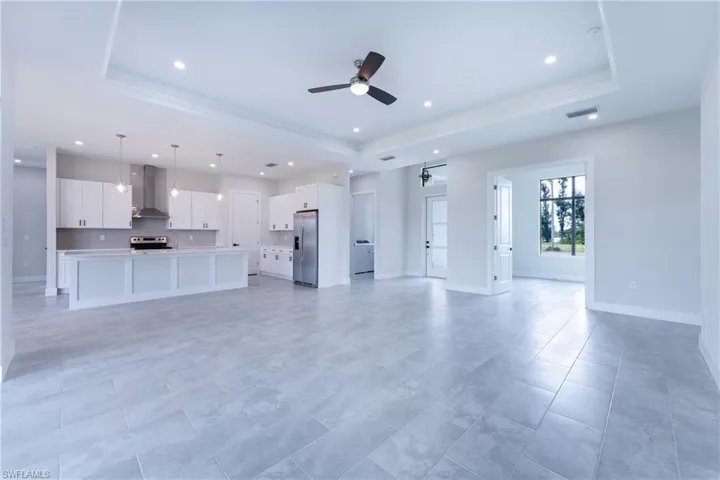 Unfurnished living room with a tray ceiling, ceiling fan, and recessed lighting