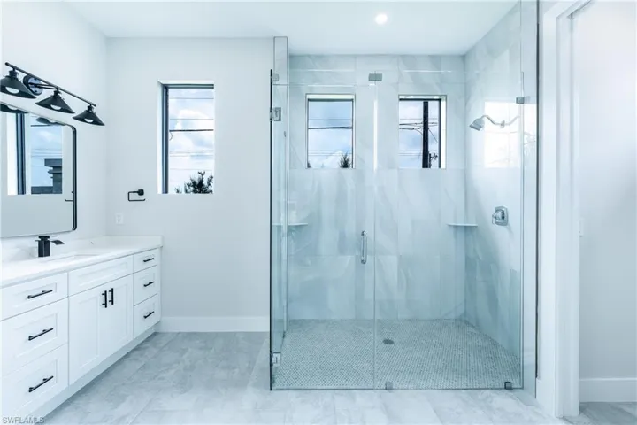 Bathroom with vanity, a marble finish shower, and recessed lighting