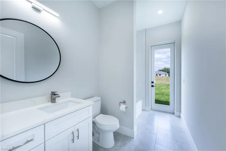 Bathroom featuring vanity, a tub to relax in, light tile patterned flooring, and recessed lighting