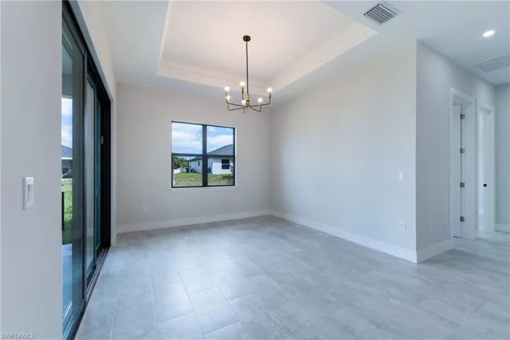 Spare room with a tray ceiling and a chandelier