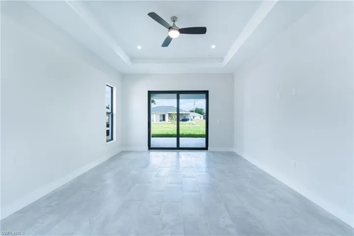 Unfurnished room featuring a ceiling fan, a raised ceiling, and recessed lighting