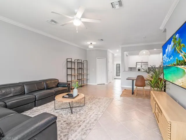 Tiled living room with crown molding and ceiling fan