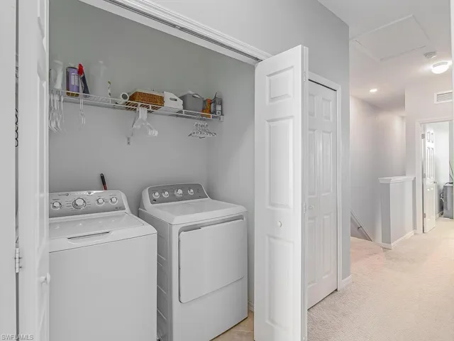 Washroom with light colored carpet and separate washer and dryer
