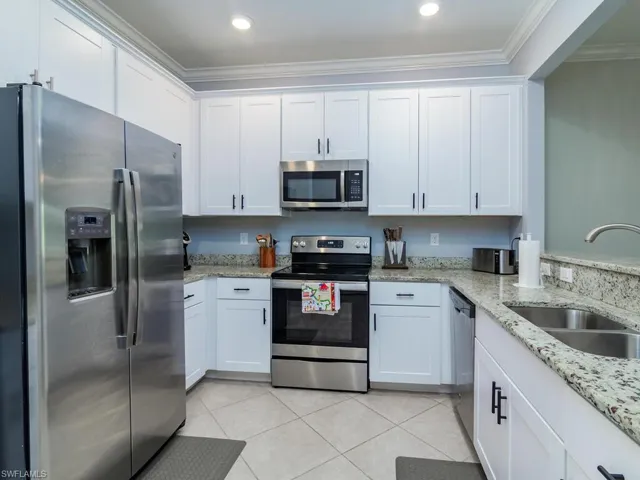 Kitchen featuring white cabinetry, ornamental molding, sink, and appliances with stainless steel finishes