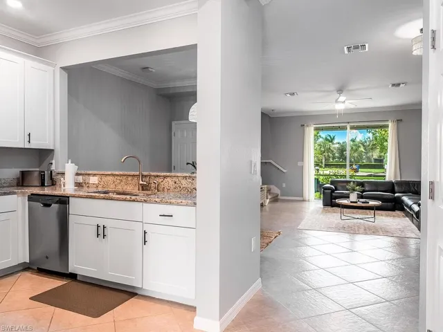 Kitchen with ceiling fan, white cabinets, stainless steel dishwasher, and light tile floors