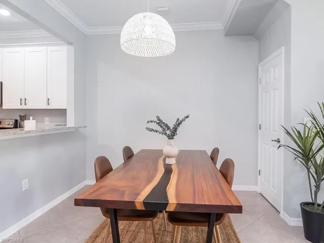Tiled dining room featuring an inviting chandelier and ornamental molding