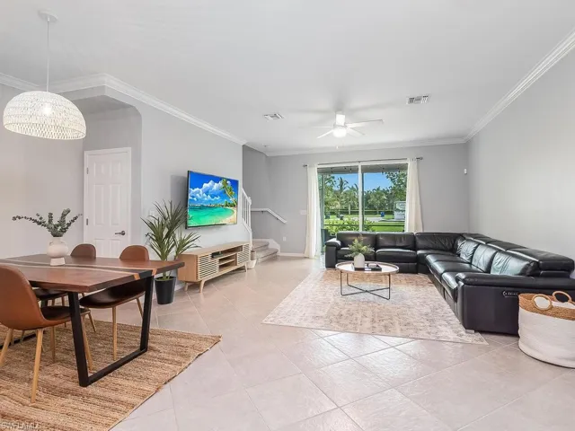 Living room featuring ceiling fan, crown molding, and light tile floors