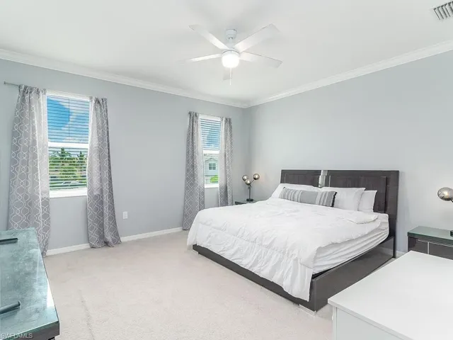 Bedroom featuring carpet, ceiling fan, and crown molding