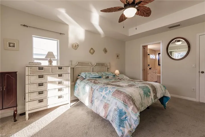 Bedroom featuring ensuite bath, ceiling fan, and carpet