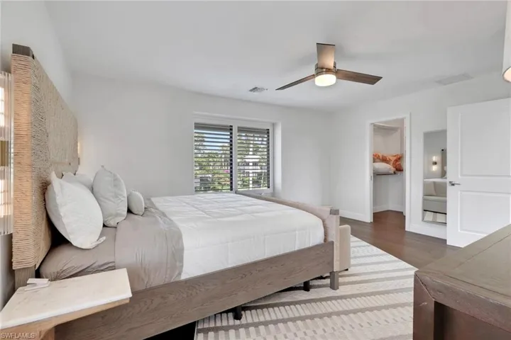Bedroom featuring a walk in closet, ceiling fan, and dark wood-style floors