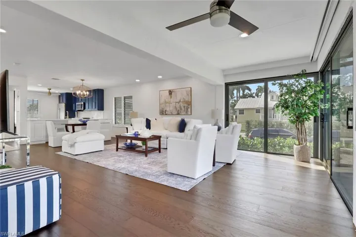 Living room with a chandelier, healthy amount of natural light, recessed lighting, dark wood finished floors, and a ceiling fan